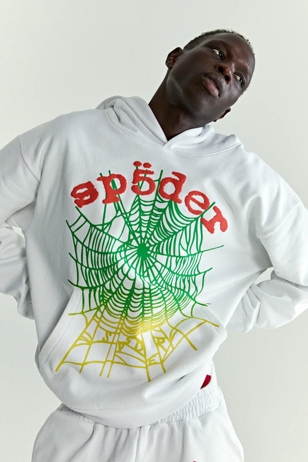 A person wearing the Sp5der “Toxic Web” Hoodie – White & Neon Lime 440GSM Heavyweight Oversized Streetwear Pullover stands with arms behind their back against a plain light background.