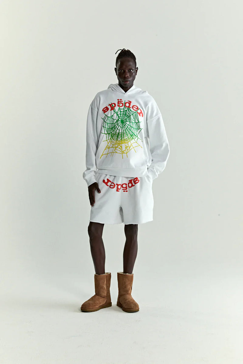 A person stands against a white background in the Sp5der “Toxic Web” Hoodie – White & Neon Lime 440GSM Heavyweight Oversized Streetwear Pullover, paired with white shorts featuring red text and brown boots for a bold Y2K streetwear look.