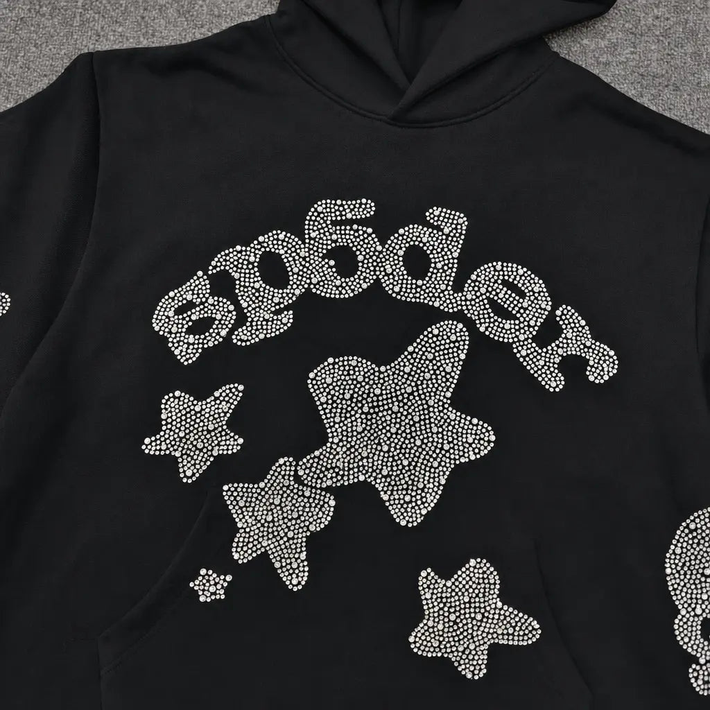 The Sp5der Black Rhinestone Star Logo Hoodie is made from 100% cotton and features "Sp5der" and star designs on the front in white rhinestones—ideal for streetwear style.