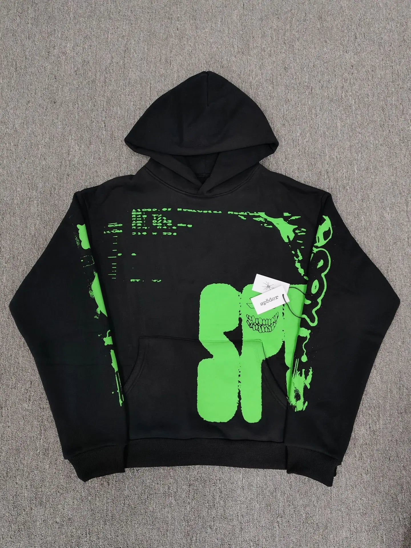 Sp5der black hoodie with neon green skull graphic and oversized logo print laid flat