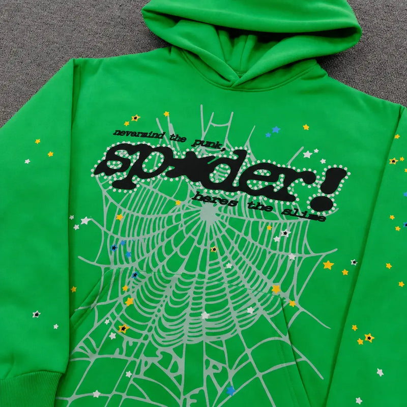 The Sp5der Neon Green Spiderweb Graphic Pullover Hoodie features a bold spiderweb design, colorful stars, and black "spider!" and "reversing the punk" text, shown laid flat on a gray surface.