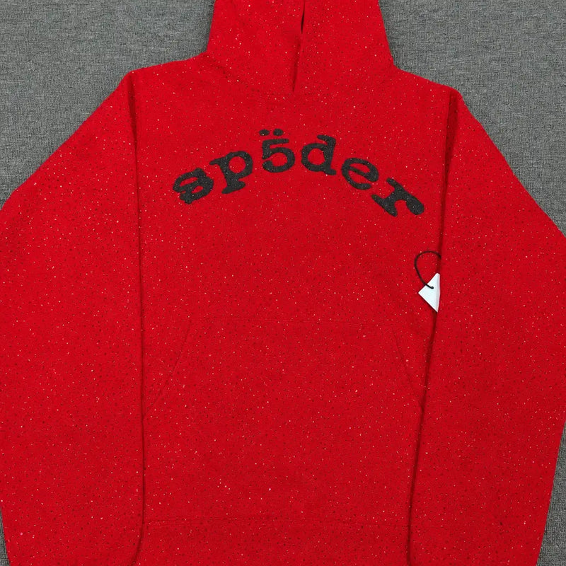 The Sp5der Red Glitter Knit Hoodie with Black Arch Logo features a hood, black stylized "sp5der" lettering across the chest, and a white side tag. This streetwear hoodie is displayed flat on a gray surface.