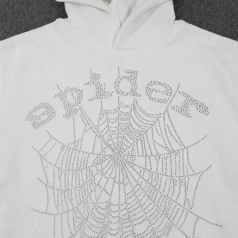 The Sp5der White Rhinestone Spiderweb Crystal Logo Hoodie is a streetwear pullover featuring "Spider" and a large crystal spiderweb design on the front, both made with shiny rhinestones.