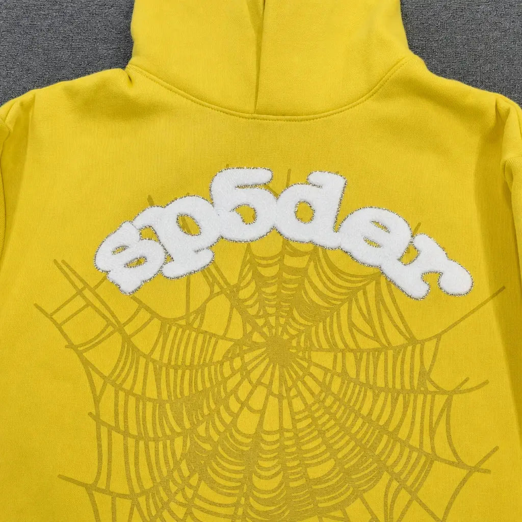 The Sp5der Yellow OG Web Graphic Pullover Hoodie showcases a striking spiderweb graphic and "sp5der" in bold white letters on the upper back, making it a standout piece for streetwear enthusiasts.