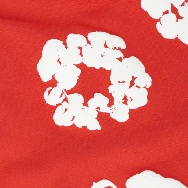 The Red “Cotton Wreath” Denim Tears Sweatpants feature a bold white abstract floral print on bright red fabric, reminiscent of the brand's iconic hand-painted motif for an artistic streetwear look.