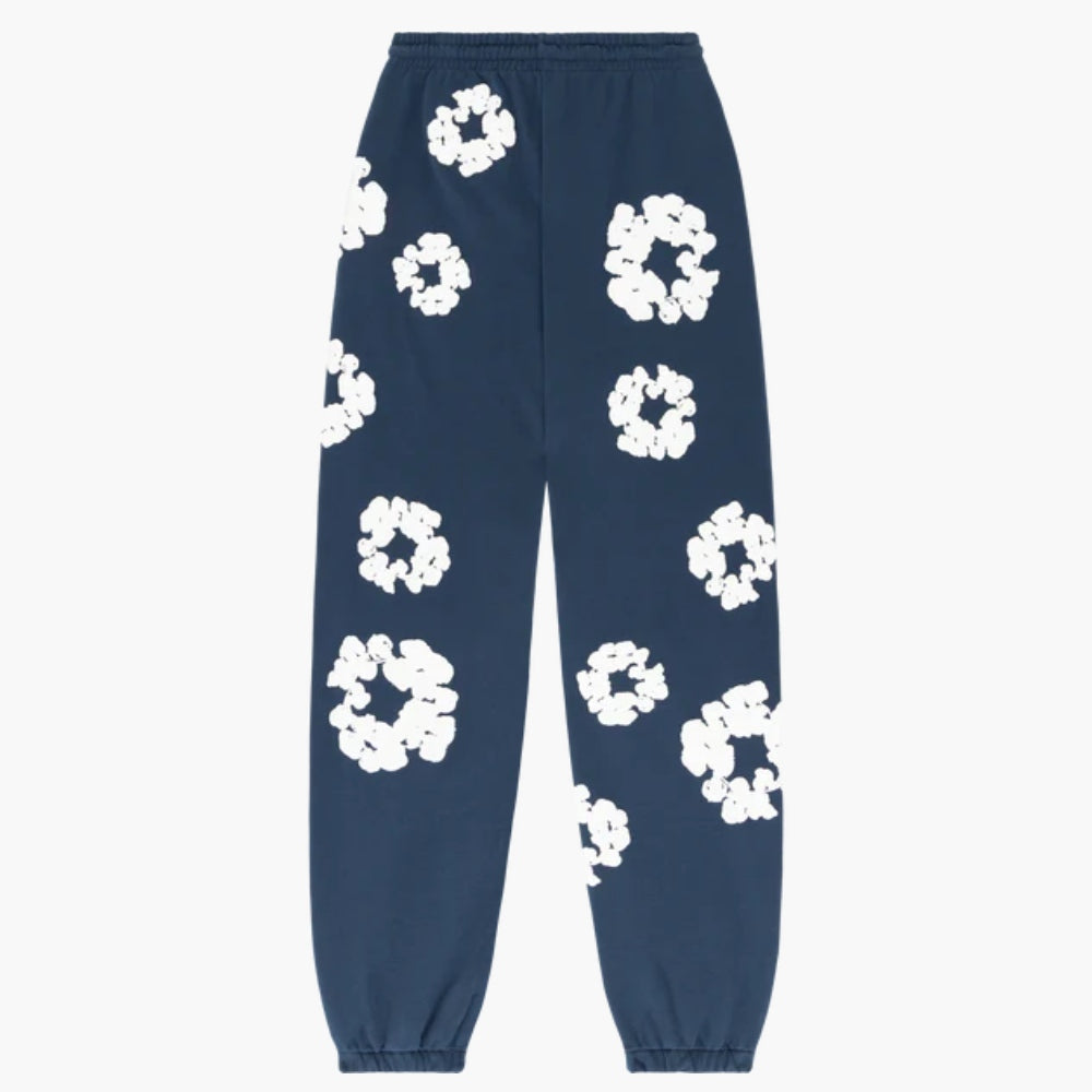 Navy Blue “Cotton Wreath” Denim Tears Sweatpants featuring white floral print, elastic waistband, and elasticated cuffs—stylish streetwear pants with abstract patterns scattered across the fabric.
