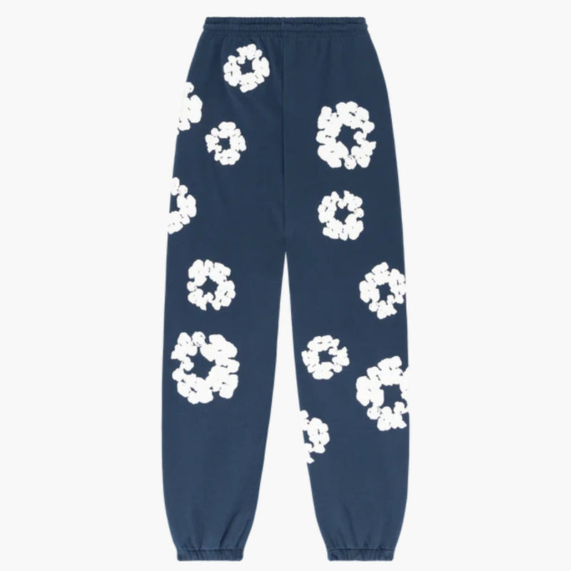 Navy Blue “Cotton Wreath” Denim Tears Sweatpants featuring white floral print, elastic waistband, and elasticated cuffs—stylish streetwear pants with abstract patterns scattered across the fabric.