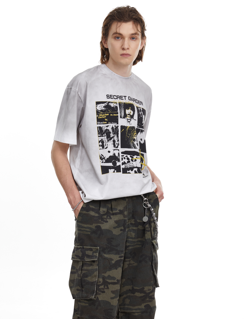Light gray oversized graphic tee with Secret Garden collage print and black text on a model, styled with camo cargo pants