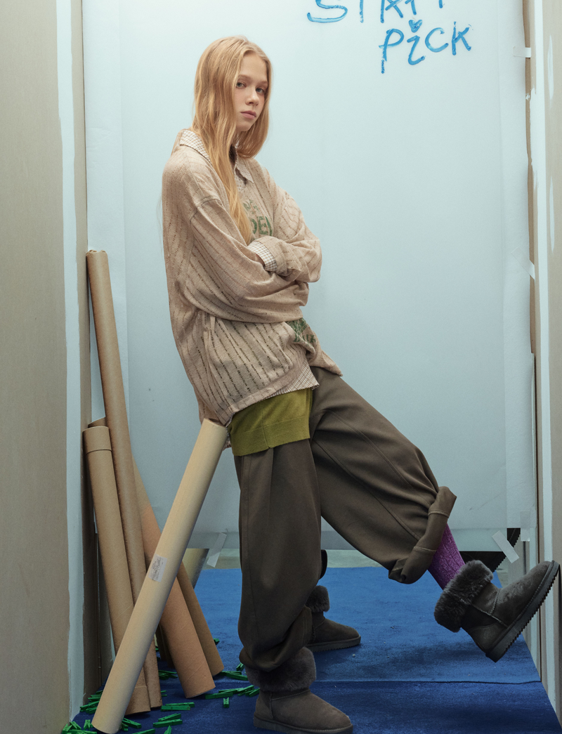 Beige mesh top layered over shirt, side view with one leg raised