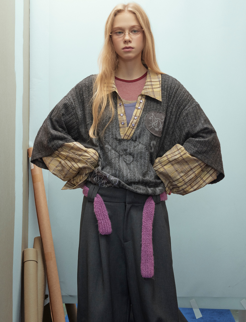 Front view of black layered bear graphic sweater with plaid sleeves on model
