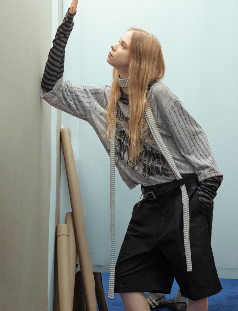 Side view of gray layered sweater top with black striped sleeves on model