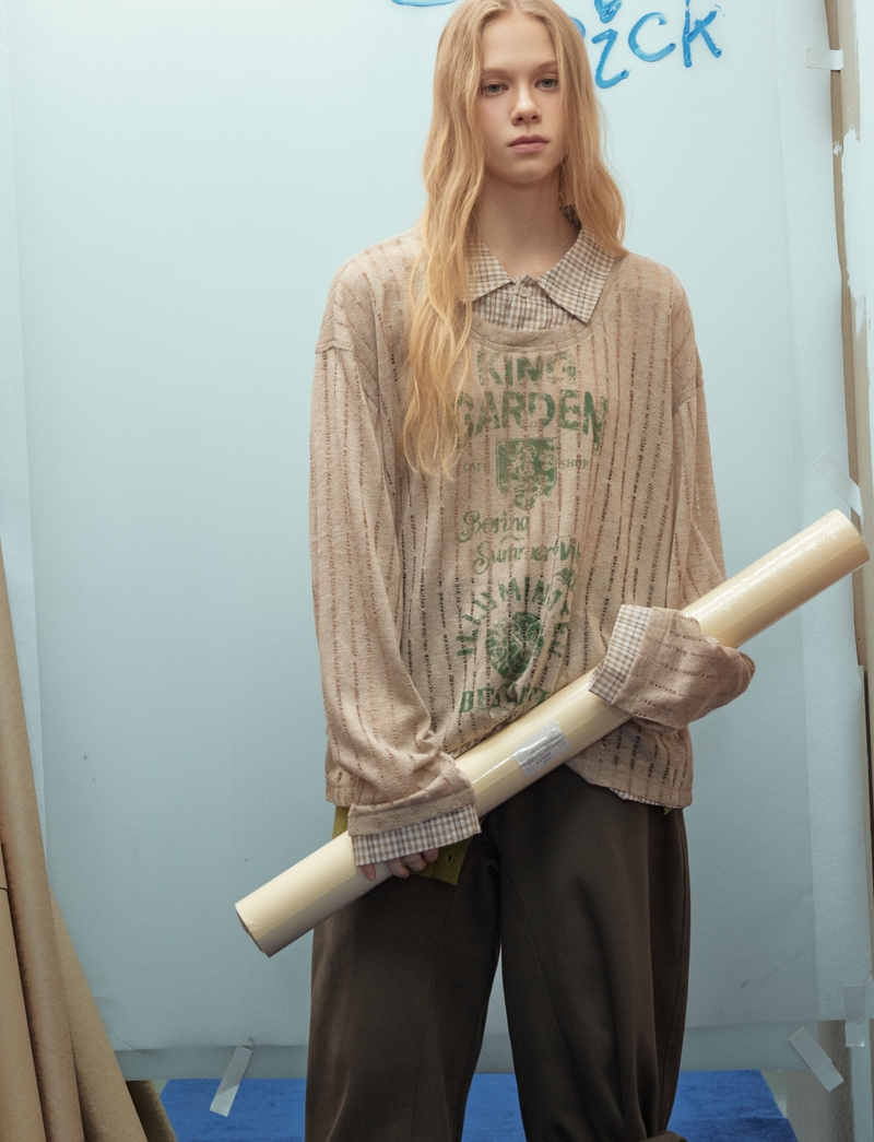 Beige graphic mesh top with plaid collar, model holding rolled paper