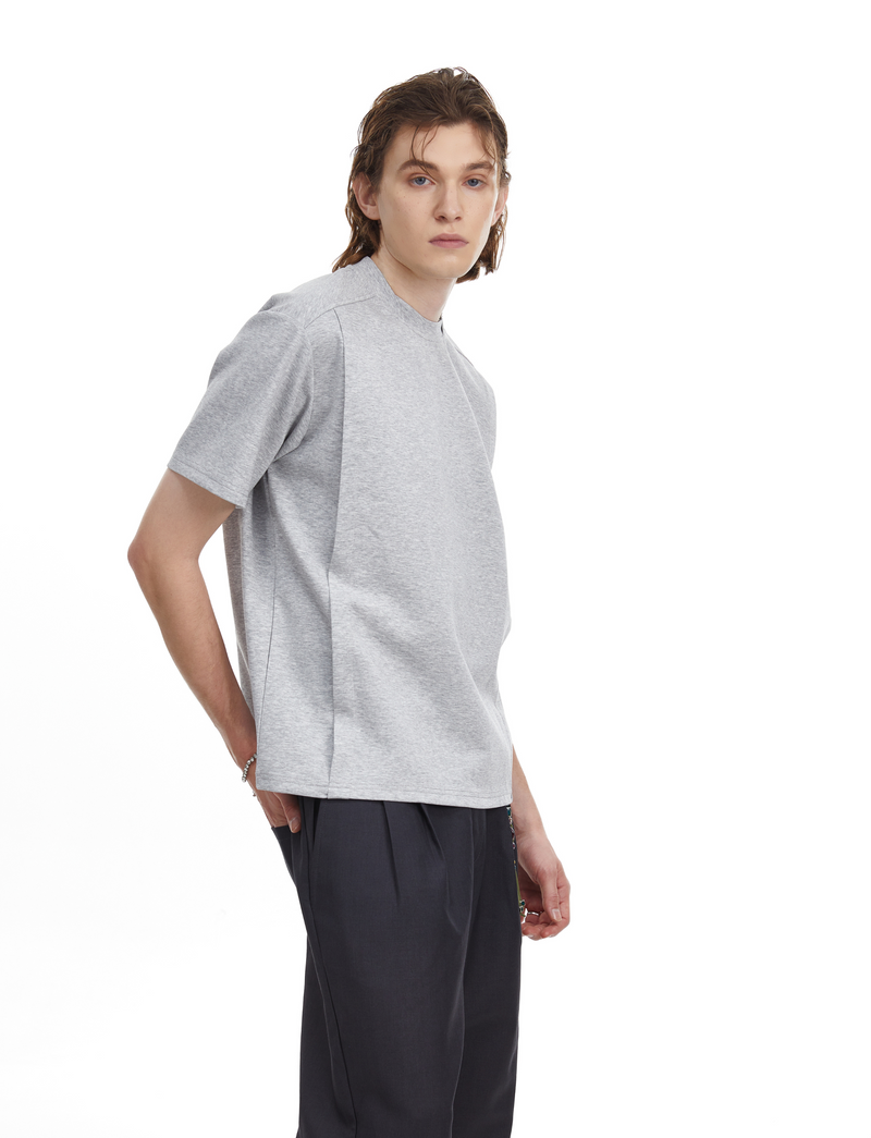 Model wearing a light gray structured oversized tee with clean minimal streetwear styling on a white background