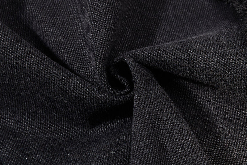 Close-up of black denim fabric folds showing the textured weave and matte finish