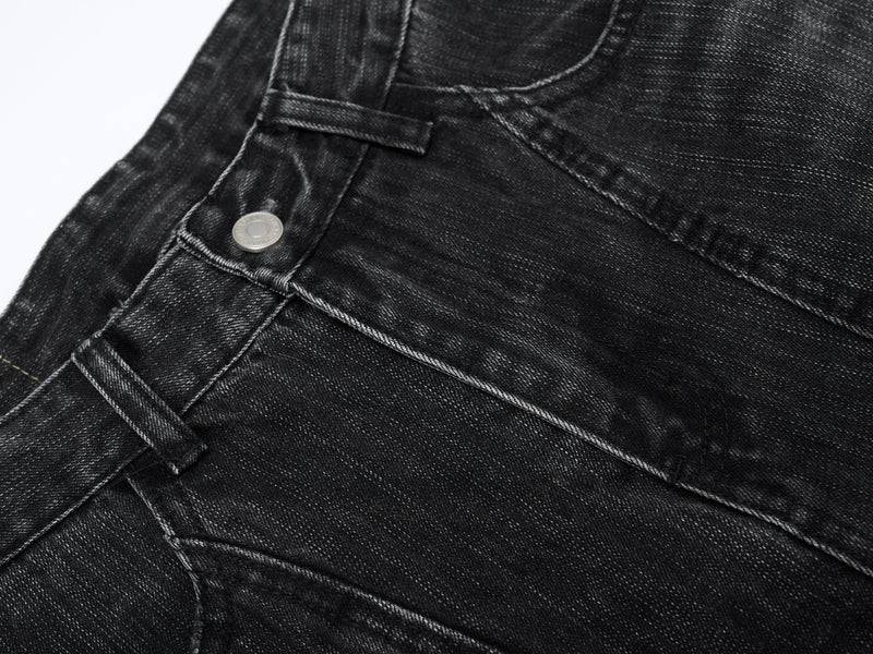 Close-up of black denim front pocket area with curved stitching and metal rivet