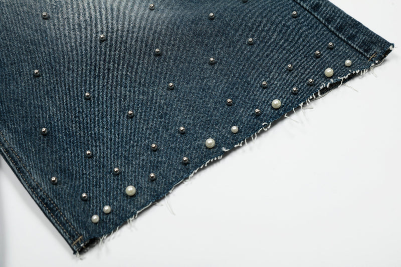 Close-up of studded denim shorts hem with frayed edge and raw finish