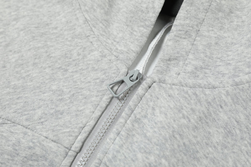 Close-up of light gray hoodie zipper and front seam with gray pull tab