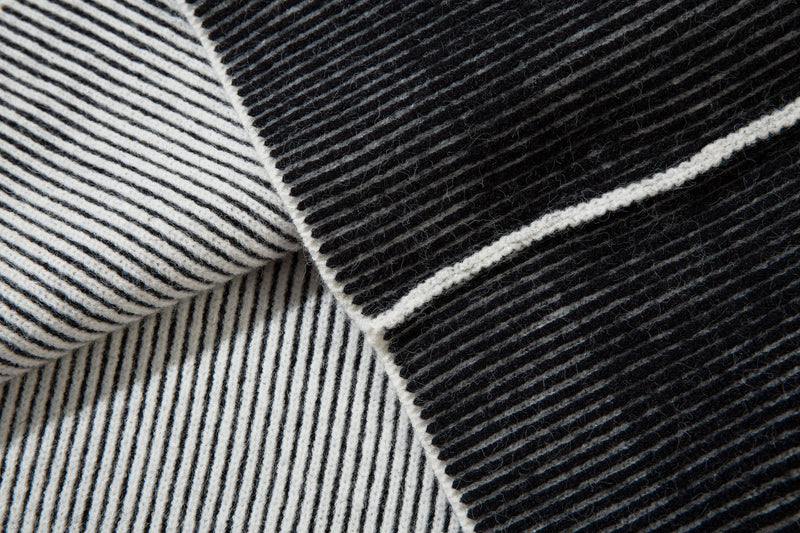 Close-up of black and white striped ribbed knit sleeves crossing