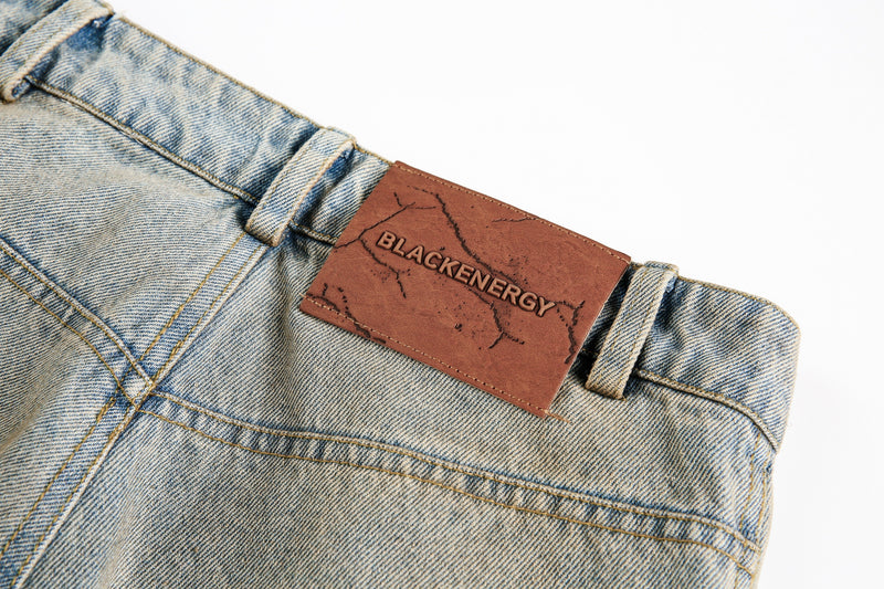 Back waistband close-up with brown BLACKENERGY label on washed denim jeans