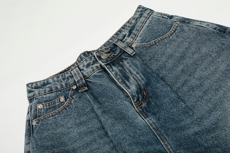 Close-up of front waistband on blue jeans with button, belt loops, and stitch detail