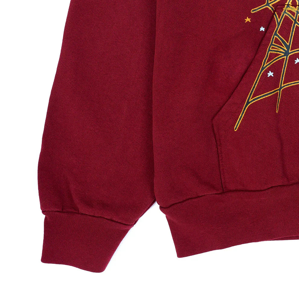 A close-up of the Burgundy Graphic Hoodie with Spider Web Print – a 440GSM heavyweight comfort fit pullover featuring yellow line art, white star and spider web prints on the pocket and sleeve, plus soft ribbed cuffs and hem.