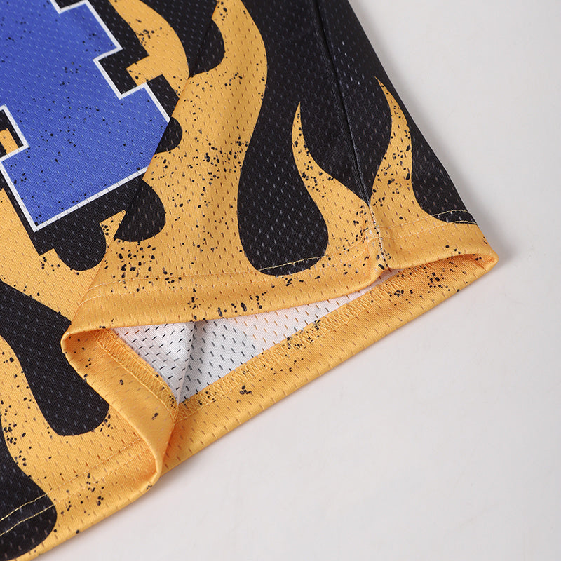 Black and yellow mesh football jersey hem with flame graphics and blue number print, close-up of breathable streetwear fabric