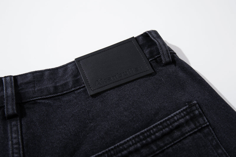 Close-up of black logo patch at the back waistband on washed black jeans