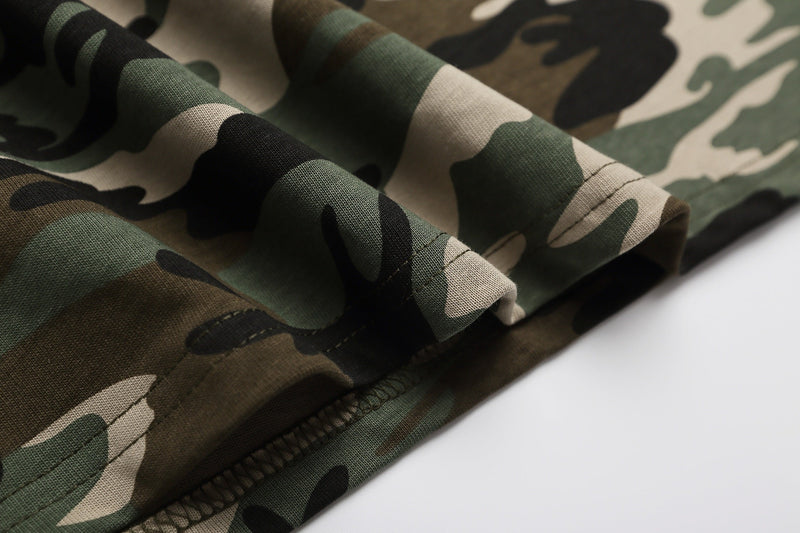 Close-up of folded camo polo shirt fabric in green, beige, and black with visible stitching and textured knit