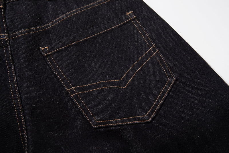 Close-up of back pocket on dark wash denim jeans with tan contrast stitching