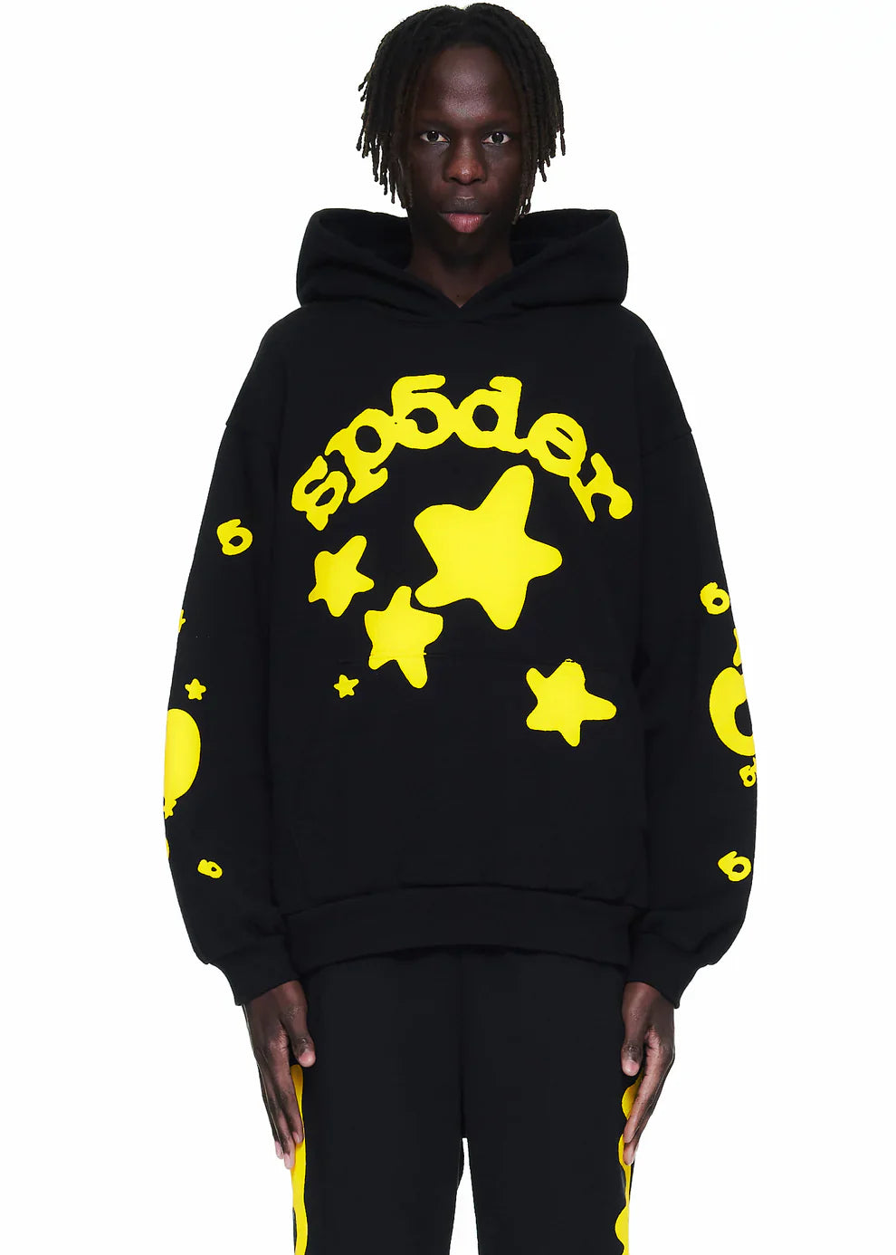 Wearing the Black Graphic Hoodie with Star Lettering Print—this comfort fit pullover features bold yellow stars, “sp5der” lettering, a large hood, and pairs well with matching black pants for standout streetwear style.