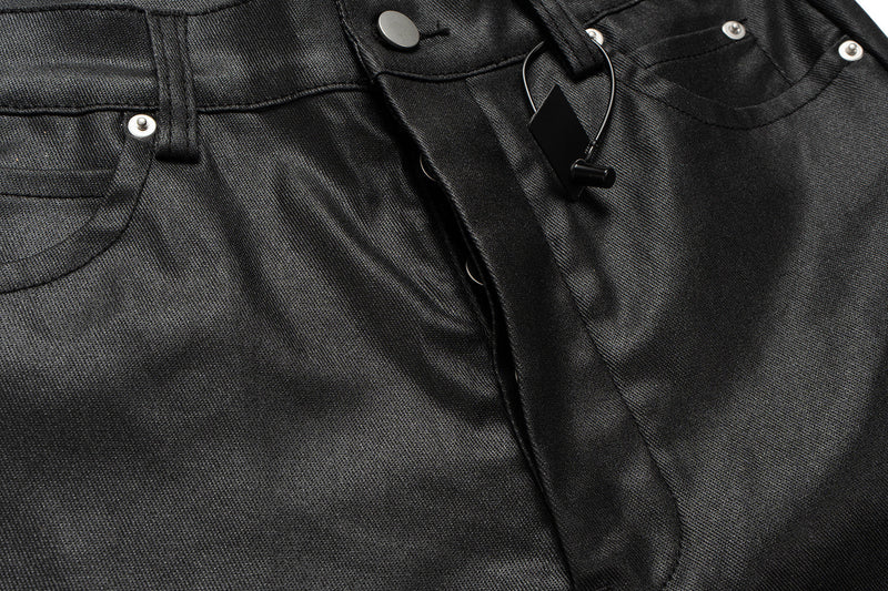 Front waist close-up of black leather-effect pants with snap button and hanging drawstring
