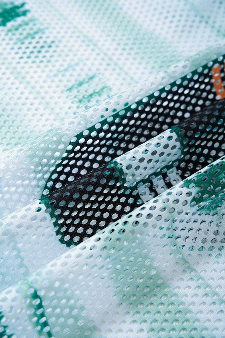 Close-up of a white and green mesh jersey with black varsity-style lettering and perforated athletic fabric texture