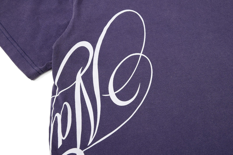 Purple washed streetwear tee with large white script crest graphic on the chest