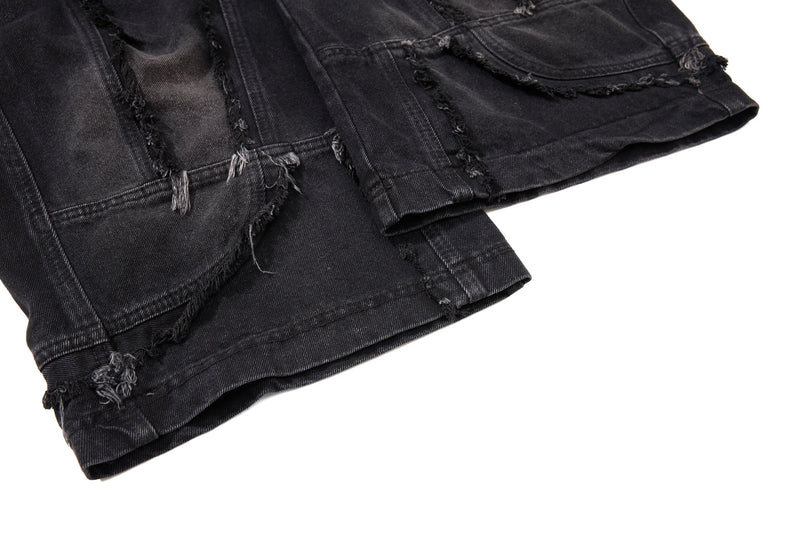 Close-up of black denim hem with frayed panel seams and folded wide-leg cuff