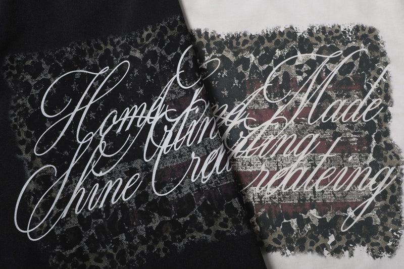 Close-up of overlapping black and white tee graphics with camo script print