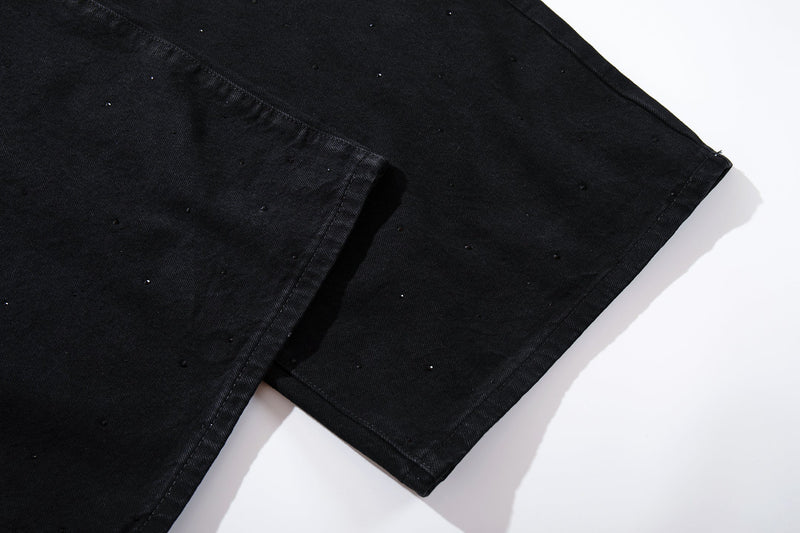Close-up of the hem of black wide-leg denim jeans with scattered rhinestones