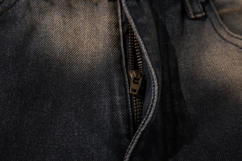 Close-up of the front zipper on black fade denim with dark metal YKK zipper teeth