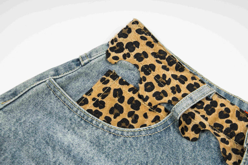 Close-up of waistband loops and leopard print patch detail on light wash denim shorts