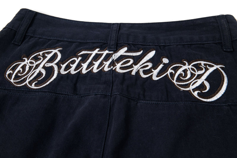 Embroidered script across the back waistband of black cargo pants, close-up