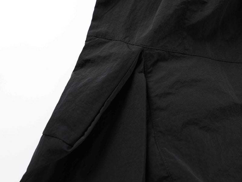 Close-up of black shorts side seam and draped panel detail