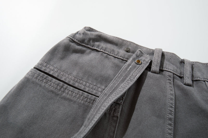 Close-up of gray jeans waistband side with snap button and belt strap detail
