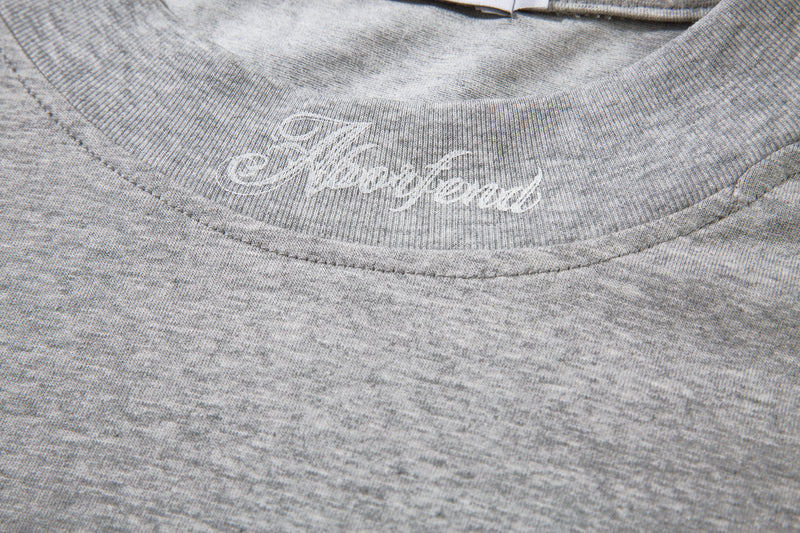 Close-up of the light gray tee front neckline with embroidered script detail