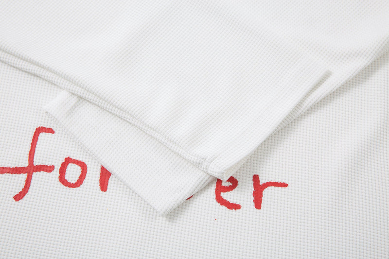 White long sleeve tee sleeve hem laid over printed body, showing waffle knit texture