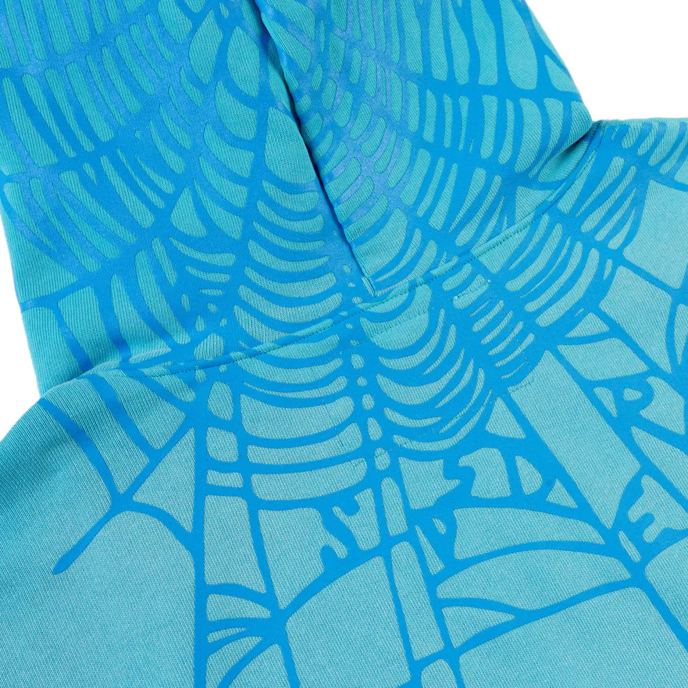 Close-up of a turquoise fabric with star detail and bright blue spider web back print, part of the Turquoise Graphic Hoodie – Comfort Fit Pullover Hoodie. Fabric appears folded, suggesting it’s from the pullover hoodie garment.