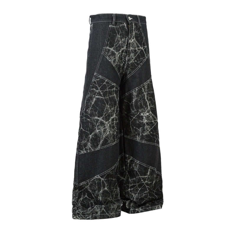Black wide-leg jeans with cracked white pattern, angled side view