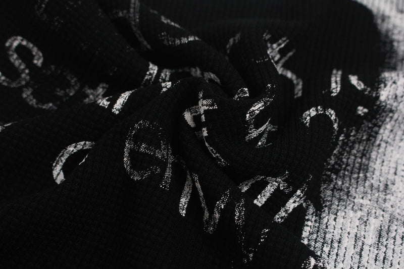 Close-up of black fabric with distressed white gothic cross graphics on an oversized streetwear tee
