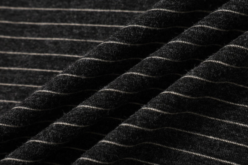 Close-up of black striped knit fabric with soft texture and thin white horizontal lines on a streetwear tee