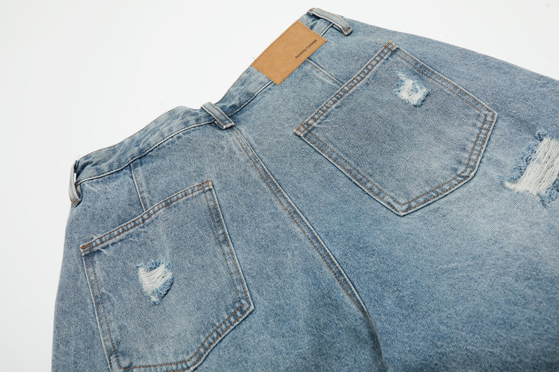 Back close-up of light blue denim shorts with leather logo patch and back pocket detail