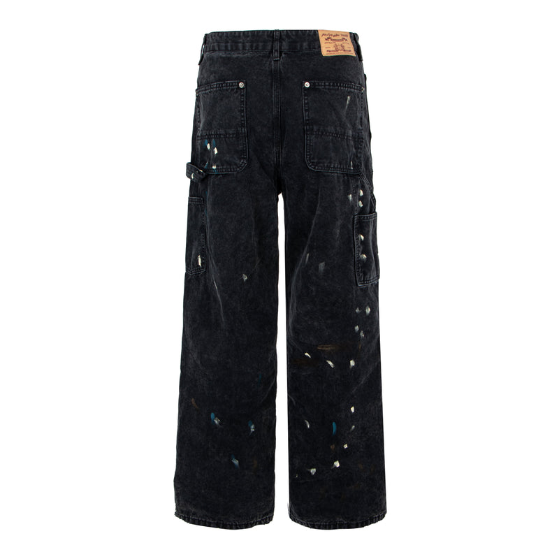 Back view of black distressed denim pants with patch pockets and paint splatter