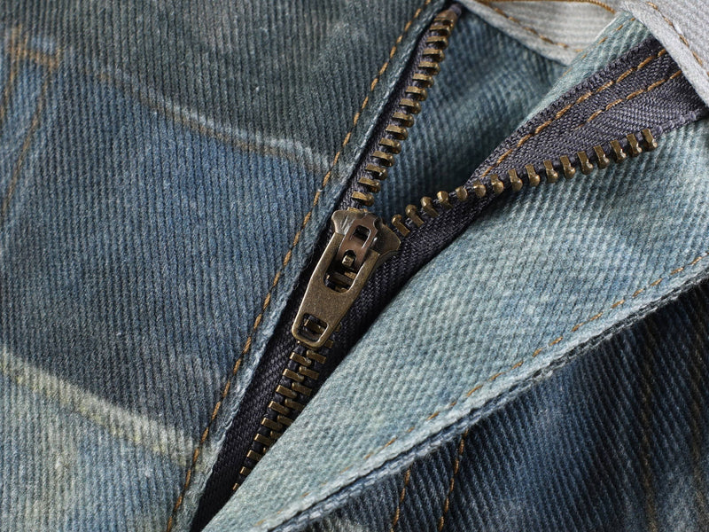 Close-up of metal zipper on layered fade distressed denim